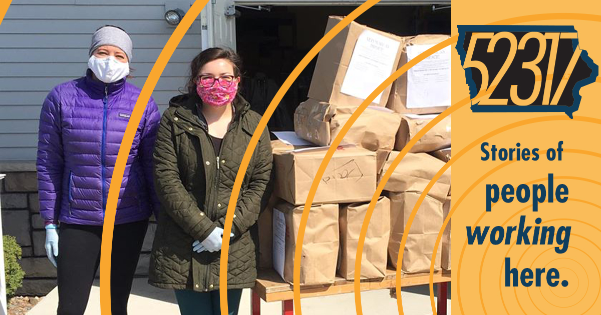 people wearing protective face masks standing beside a cart of donated goods