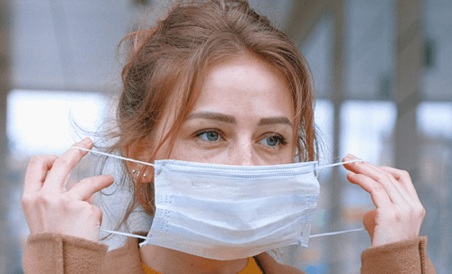 A woman putting on a mask to protect herself and others from coronavirus