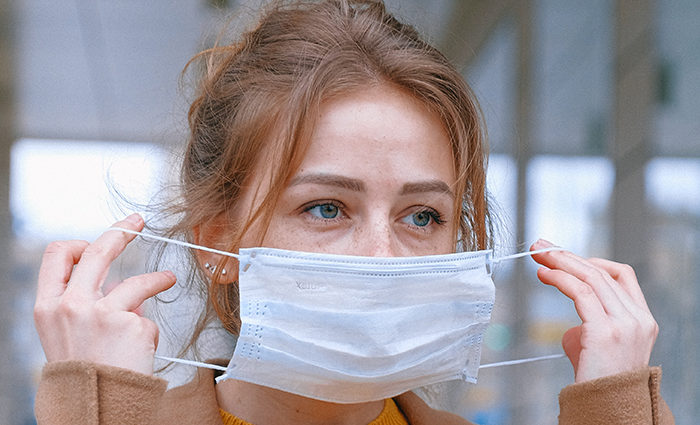 A woman putting on a mask to protect herself and others from coronavirus