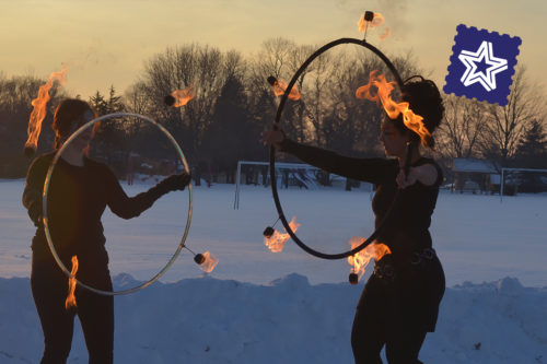 Two people spinning fire hula hoops