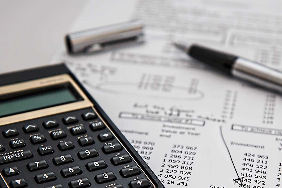 A calculator, pen and marked up financial document.