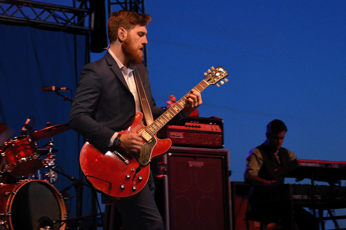 A musician plays a guitar at dusk on the stage at Blues & BBQ