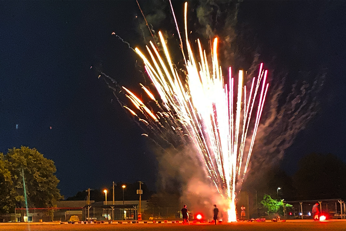 White fireworks explode against a night sky.