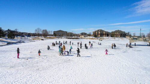 People stand on the ice of a Liberty Centre Pond during a mostly sunny winter day for ice fishing.