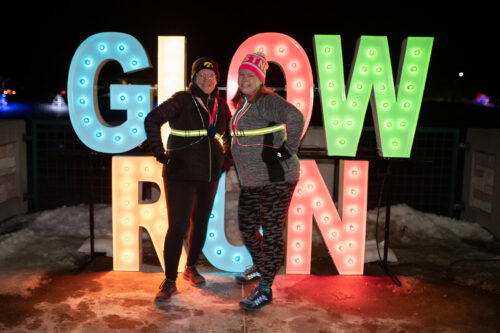 Two people in front of large Glow Run letters