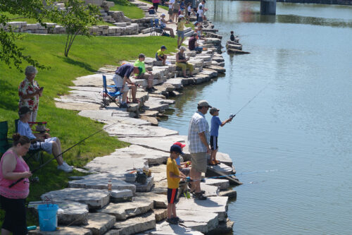 A large number of people enjoy a sunny day of fishing at Liberty Centre pond in North Liberty on a late spring day.